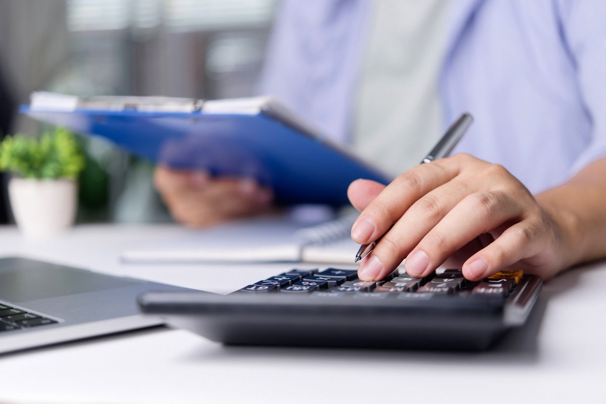 Person using a calculator and holding a document