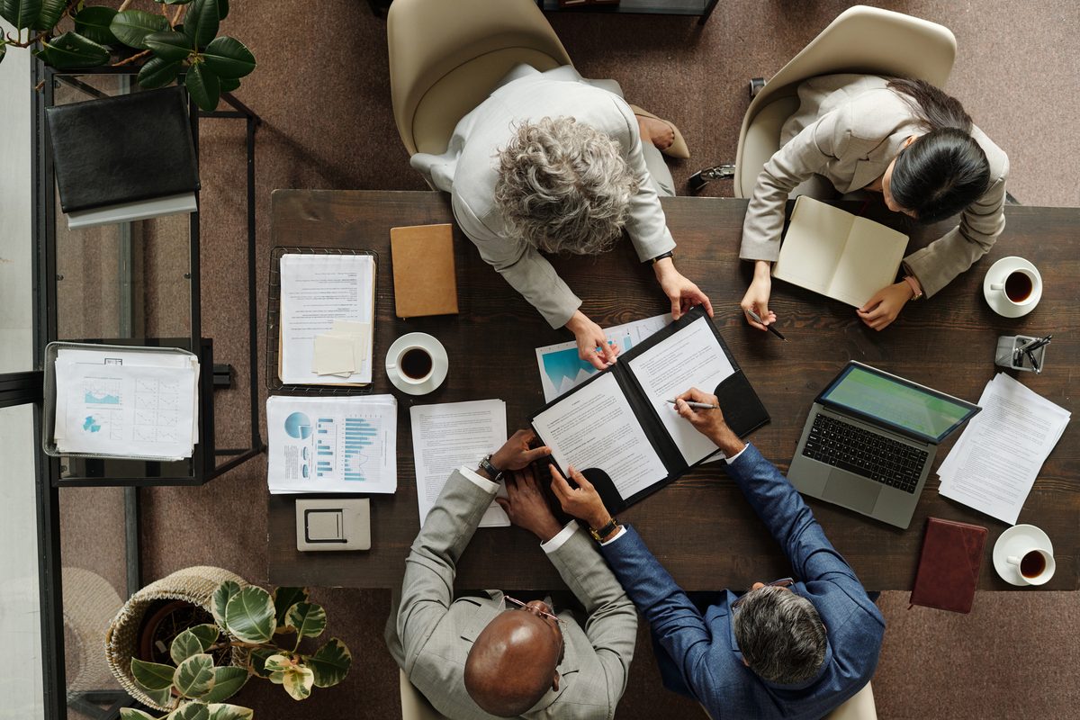 An aerial view of four people in a meeting around a table