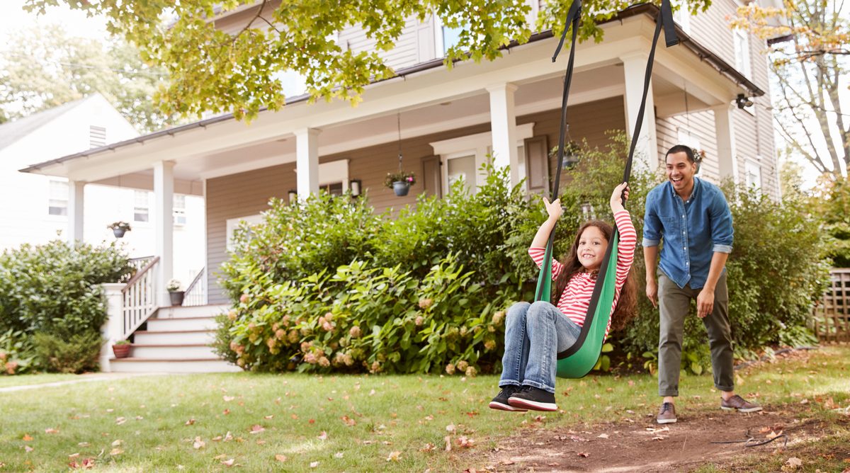 A father pushing his daughter on a garden swing